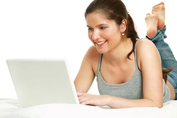 Casual barefoot girl with laptop on her bed — Stock Photo, Image