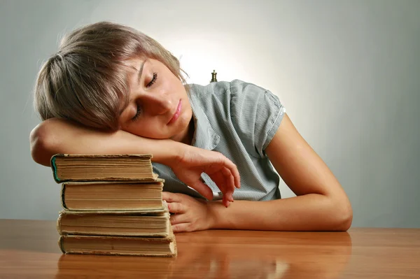 Giovane donna che dorme su pile di libri — Foto Stock