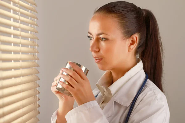 Jeune femme médecin est debout dans le bureau près de la fenêtre — Photo