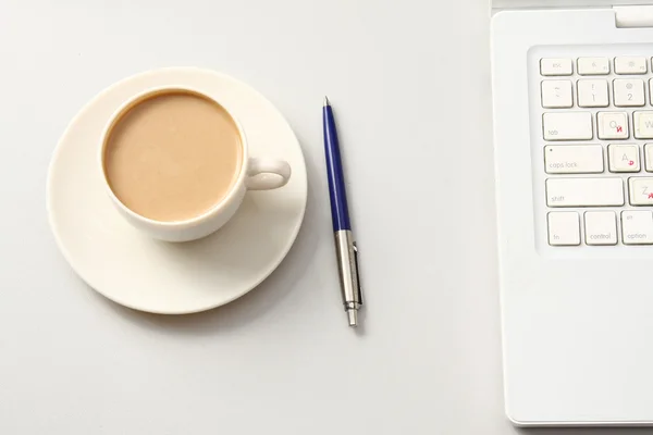 Una taza de café y una pluma cerca de un portátil — Foto de Stock