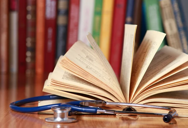 Uno stetoscopio è sdraiato con un libro sulla scrivania — Foto Stock