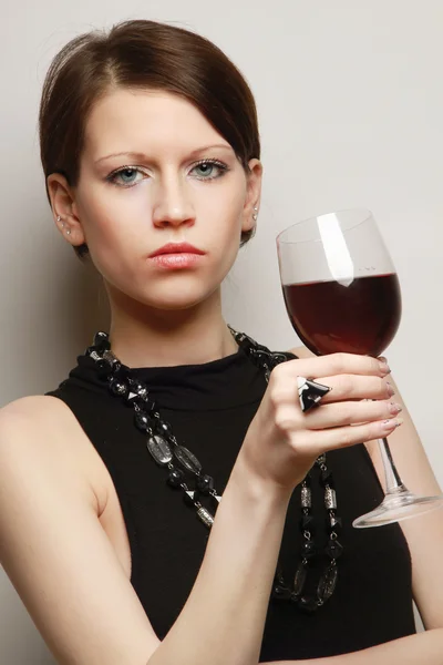Giovane donna con un bicchiere di vino vicino al muro — Foto Stock