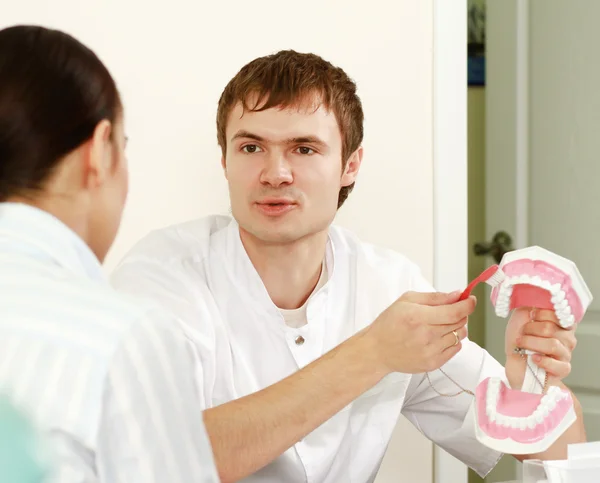 Дантист учит пациента чистить зубы — стоковое фото