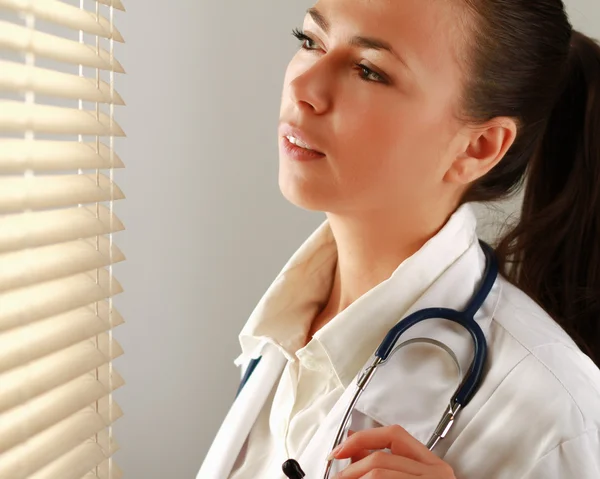 Vrouw arts is permanent in de buurt van venster. — Stockfoto