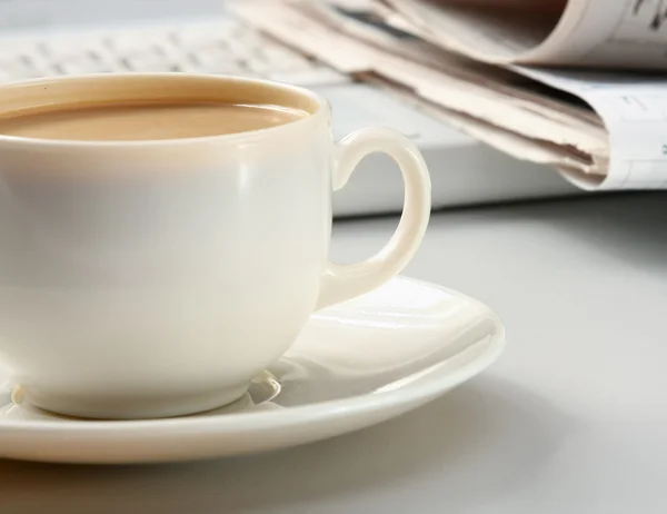 Cup of coffee near the laptop and newspapers. Royalty Free Stock Images