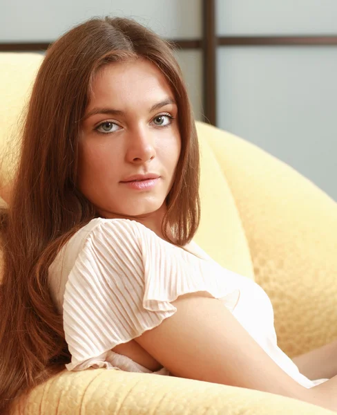 Una giovane donna sorridente seduta sul divano — Foto Stock