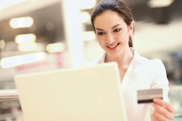 Femme heureuse assise sur le bureau et faisant du shopping en ligne — Photo