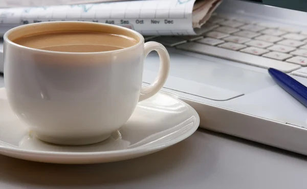 Tasse Kaffee in der Nähe von Laptop und Zeitungen. — Stockfoto