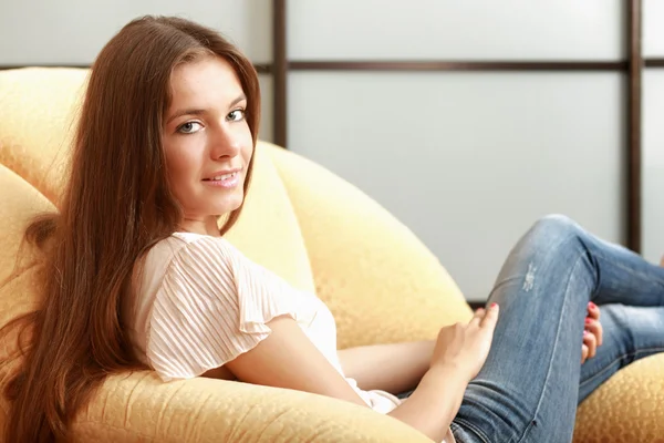 Kobieta siedząca na kanapie — Zdjęcie stockowe