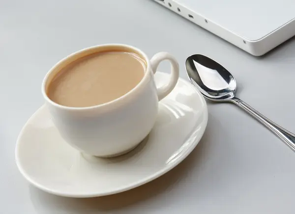 Tasse de café près de l'ordinateur portable — Photo