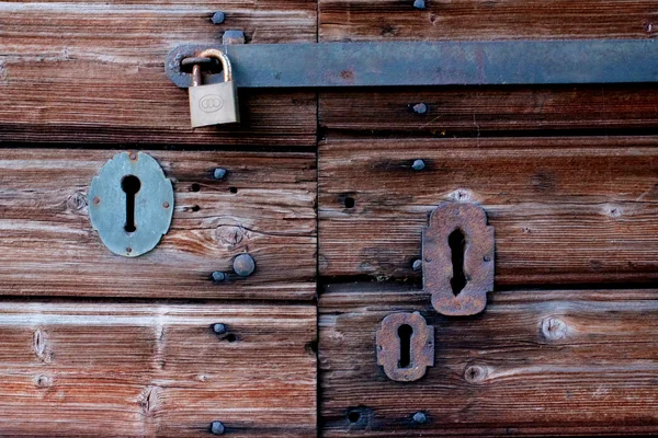 Старая деревянная дверь с четырьмя замками, покрытыми ржавчиной — стоковое фото