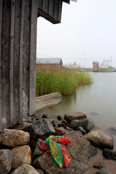 Kleurrijke handdoek opleggen rotsen naast houten hut — Stockfoto