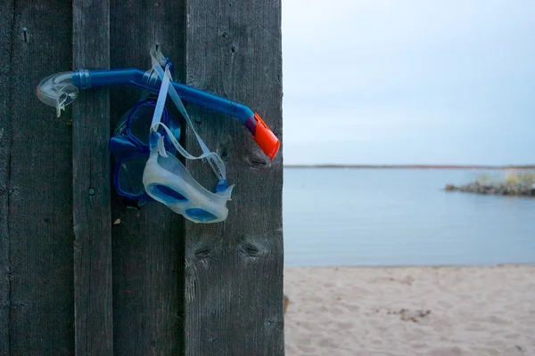 Snorkel e máscaras penduradas na parede de madeira na praia — Fotografia de Stock