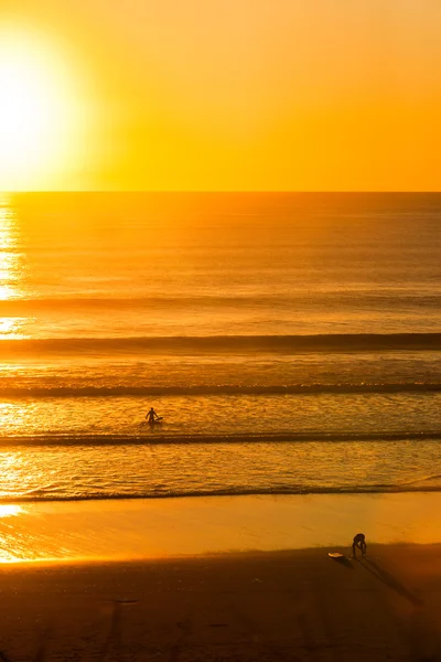 Surfistas na praia ao pôr do sol — Fotografia de Stock