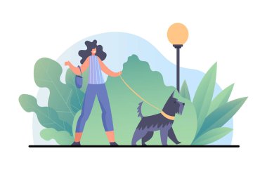 Gülümseyen genç kadın parkta köpeği gezdiriyor.