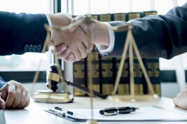 Avukatın ofisteki adama hukuki danışmanlık hizmeti vermesi üzerine el sıkışma adalet terazisi ve tokmak çekiciyle..