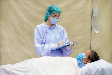 Doktor yaşlı hastaların semptomlarını inceler ve kayıtlar tutar..