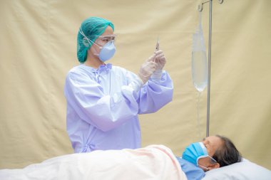 The doctor's hand holding a syringe and was about to vaccinate a senior woman patient at the clinic to prevent the spread of the virus, health medical checkup concept.