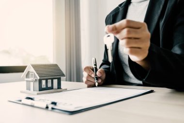 Hand a real estate agent sign with home model, key and explain the business contract, rent, buy, mortgage, loan, or insurance to the buyer woman