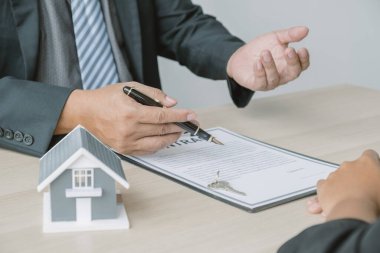 Hand a real estate agent with home model, key and explain the business contract, rent, buy, mortgage, loan, or insurance to the buyer woman.