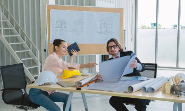Engineer team is meeting to inspect the construction blueprint drawings, work plan and distribute work before starting the building.