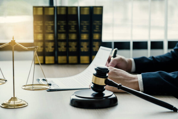 gavel hammer, Lawyer hand holding pen and providing legal consult business dispute service at the office with justice scale.