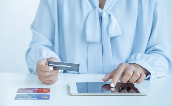 Consumer woman hand holding a mock up credit card, ready to spending pay online finance shopping according to discount products via Tablet from home office.