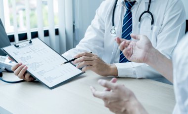 Doktor rapora işaret etti ve muayene sonuçlarını hasta adama, sağlık hizmetlerine ve sağlık kontrolüne açıkladı..