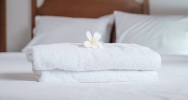 towels and Plumeria on the bed in the luxury hotel room ready for tourist travel.