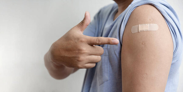 Asia man hand pointing to the shoulder with bandage has gone to vaccinate coronavirus covid19, Healthcare And Inoculation Concept.