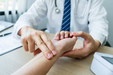 Doktor hastanın nabzını elle kontrol eder ve sonuçları kaydeder. Sağlık kontrolü konsepti..