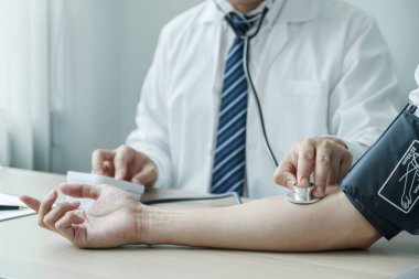 Doctor evaluates the patient with a stethoscope, blood pressure monitor and records the results, health medical checkup concept.