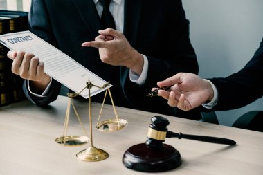 El ele tutuşma kalemi, hukuki danışmanlık hizmeti veren avukat ofiste adalet terazisi ve tokmak çekiciyle.