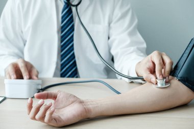 Doctor evaluates the patient with a stethoscope, blood pressure monitor and records the results, health medical checkup concept.