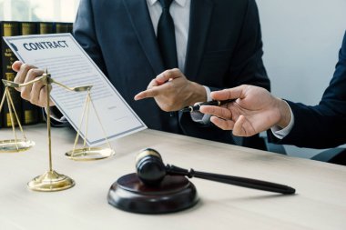 El ele tutuşma kalemi, hukuki danışmanlık hizmeti veren avukat ofiste adalet terazisi ve tokmak çekiciyle.