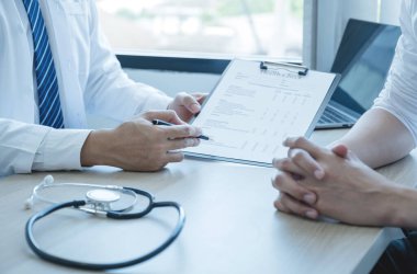 The doctor hand write report and explained the health examination results to the patient man, medical checkup concept.