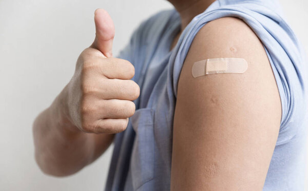 Asia man hand make thumbs up and show shoulder with bandage has gone to vaccinate coronavirus covid19, Healthcare And Inoculation Concept.