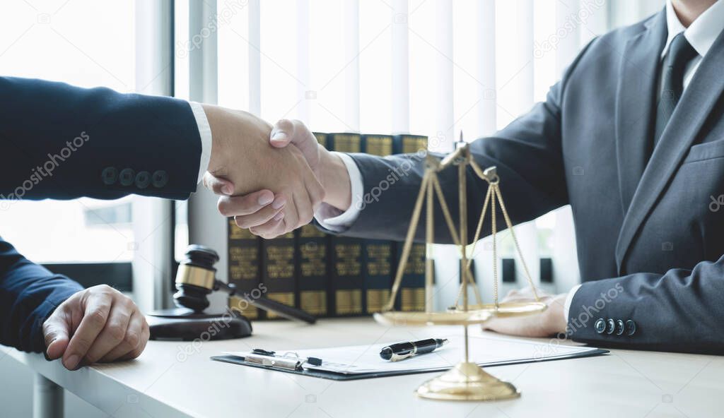 Handshake after Lawyer  providing legal consult business dispute service to the man at the office with justice scale and gavel hammer.