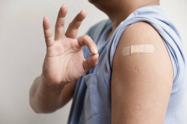 Asia man hand make ok and show shoulder with bandage has gone to vaccinate coronavirus covid19, Healthcare And Inoculation Concept.