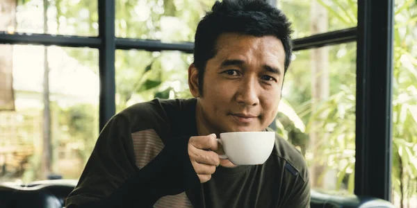 Portrait of Asia middle-aged man drinking coffee at the cafe.