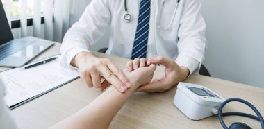 Doktor hastanın nabzını elle kontrol eder ve sonuçları kaydeder. Sağlık kontrolü konsepti..