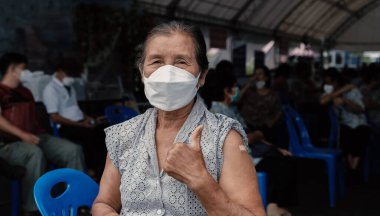Closeup of senior woman has gone to vaccinate coronavirus covid19 shoulder with bandage showing thumbs up at field hospital a place set up by the government