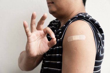 Asia man hand make ok and show shoulder with bandage has gone to vaccinate coronavirus covid19, Healthcare And Inoculation Concept.