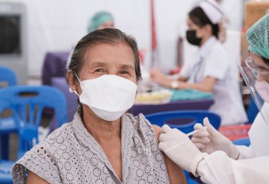 Üst sınıftan bir kadın sahra hastanesinde tıbbi personelle birlikte Coronavirus aşısı yaptırmaya gitti. Hükümet tarafından kurulan bir yer..