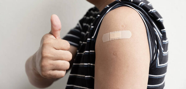 Asia man hand make thumbs up and show shoulder with bandage has gone to vaccinate coronavirus covid19, Healthcare And Inoculation Concept.