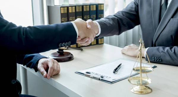 Handshake after Lawyer  providing legal consult business dispute service to the man at the office with justice scale and gavel hammer.