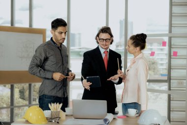 Engineer team is meeting to inspect the construction blueprint drawings, work plan and distribute work before starting the building.