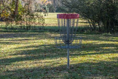 Sonbaharda güneşli bir günde, gölgede yapraklarla çevrili boş bir golf sepetinin yakın görüntüsü.