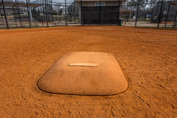 Standing in front of a pitchers mound looking towards home base in a baseball field at a empty park in early springtime closeup view