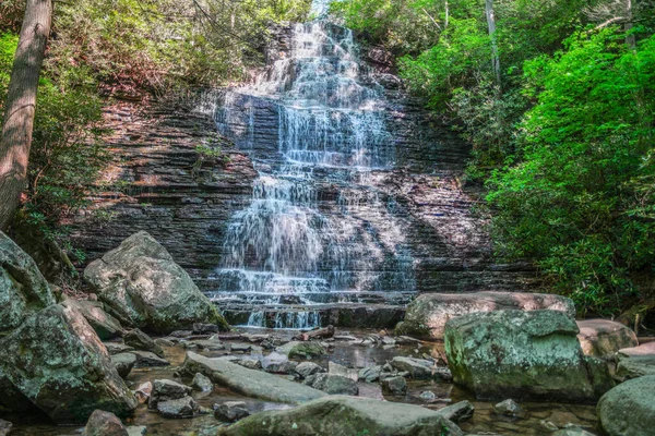春の晴れた日にテネシー州のチェロキー国有林のベントン滝で岩や岩に囲まれた浅い水に流れるカスケード滝の大きな岩壁 — ストック写真